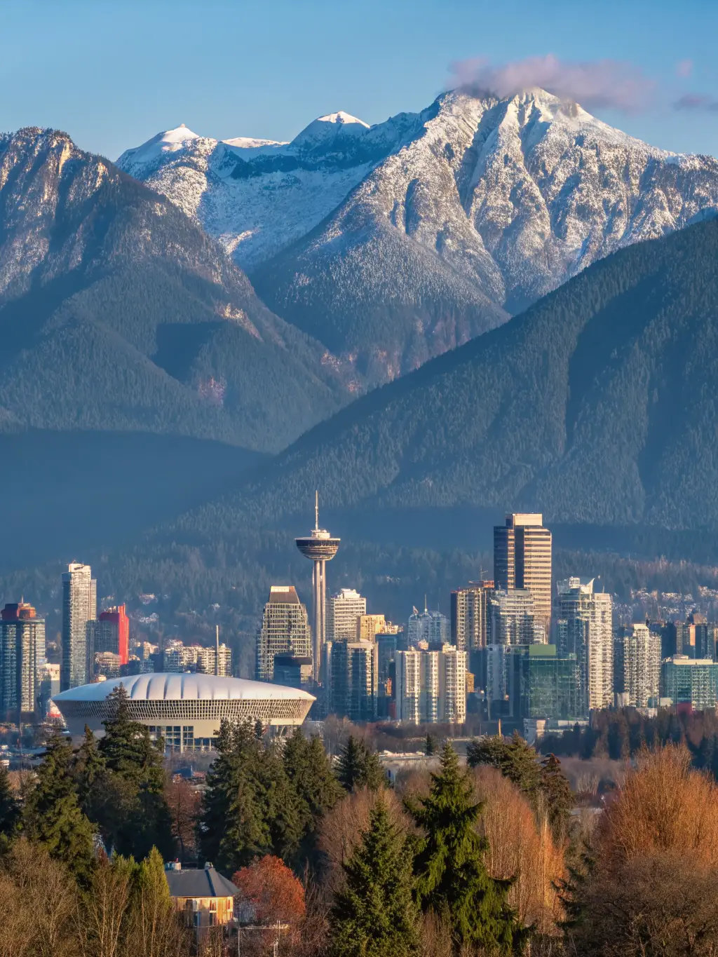 A scenic view of Vancouver, British Columbia, featuring mountains, ocean, and a modern city skyline, representing the city's focus on sustainability and technology.